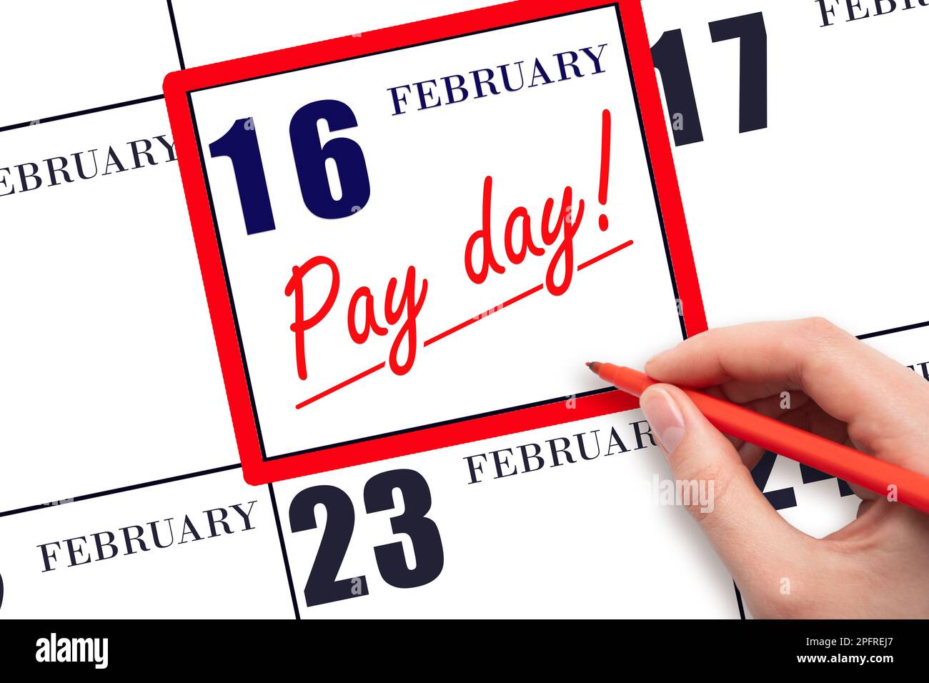 16th day of February. Hand writing text PAY DATE on calendar date February 16 and underline it. Payment due date.  Reminder concept of payment. Winter Stock Photo