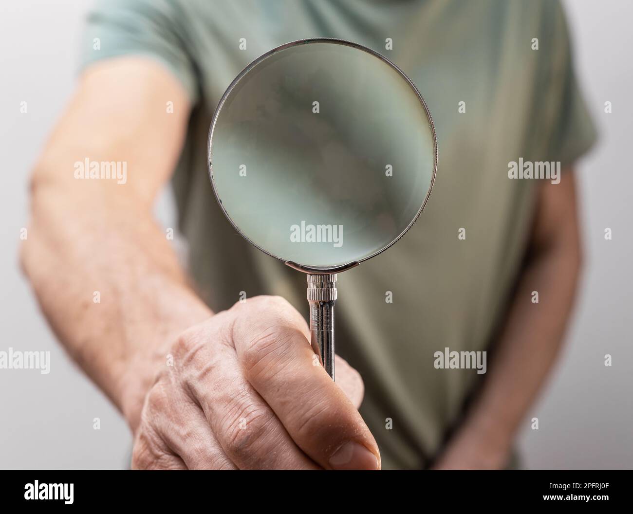 Hand holding magnifying glass, loupe, magnifier. Search information