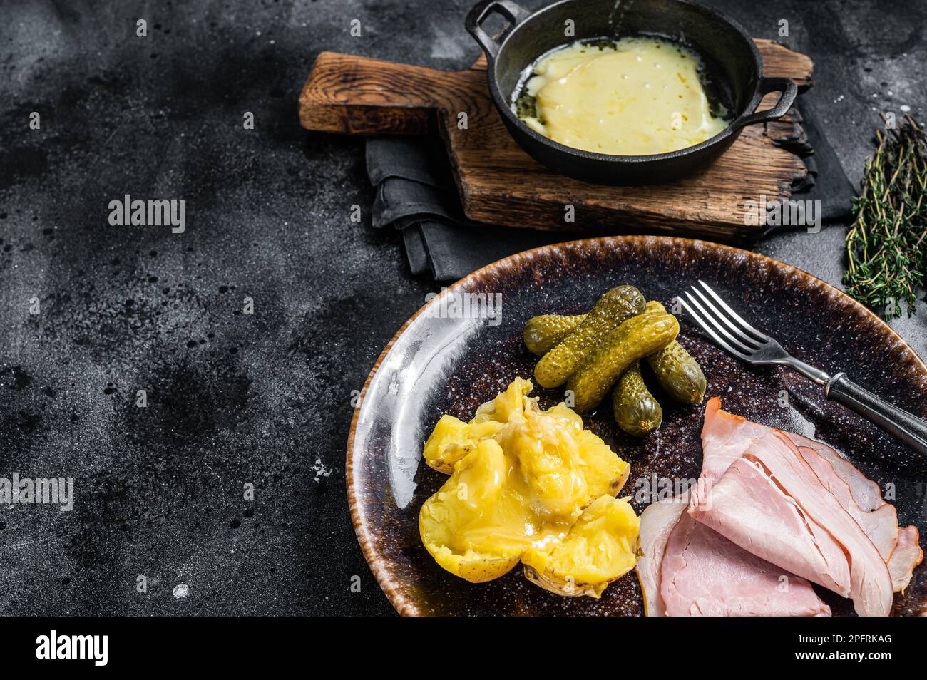 Raclette Melted cheese with boiled potato and ham on rustic plate, swiss  meal. Black background. Top view. Copy space Stock Photo - Alamy