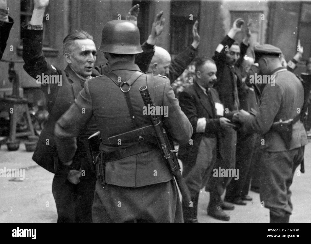 In January 1943 the nazis arrived to round up the Jews of the Warsaw Ghetto  The Jews, resolved to fight it out, took on the SS with homemade and primitive weapons. The defenders were executed or deported and the Ghetto area was systematically demolished. This event is known as The Ghetto Uprising. This image shows a SS troops arresting the Jewish department heads of the Brauer helmet factory. The Brauer 'shop', of Herman Brouer, made helmets for the German Army and employed 2 thousand people. Their workers were probably of the last Jews to be deported from the ghetto. This image is from the G Stock Photo