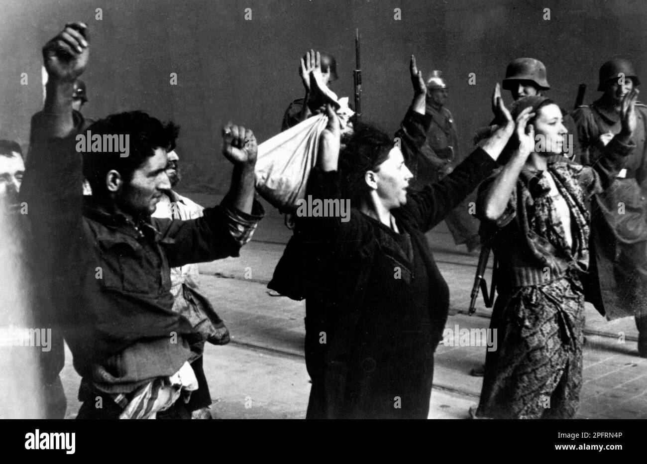 In January 1943 the nazis arrived to round up the Jews of the Warsaw Ghetto  The Jews, resolved to fight it out, took on the SS with homemade and primitive weapons. The defenders were executed or deported and the Ghetto area was systematically demolished. This event is known as The Ghetto Uprising. This image shows a group of jewish women surrendering, hands up, to German soldiers. The Woman on the right has been named as Hasia Szylgold-Szpiro.  This image is from the German photographic record of the event, known as the Stroop report. Stock Photo