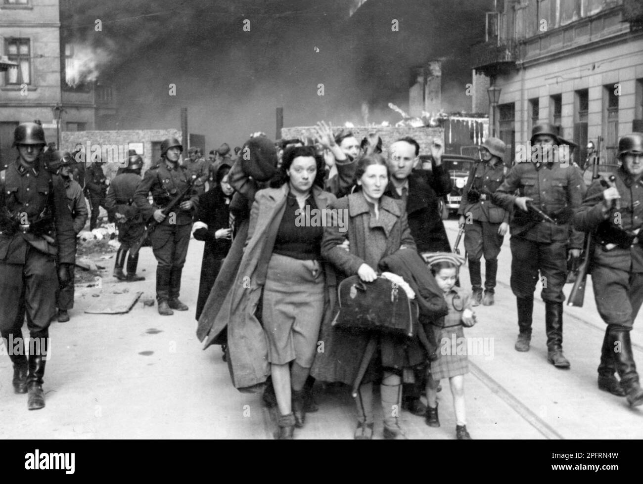 In January 1943 the nazis arrived to round up the Jews of the Warsaw Ghetto  The Jews, resolved to fight it out, took on the SS with homemade and primitive weapons. The defenders were executed or deported and the Ghetto area was systematically demolished. This event is known as The Ghetto Uprising. This image shows a column of captured women leaving the burning city.  This image is from the German photographic record of the event, known as the Stroop report. Stock Photo