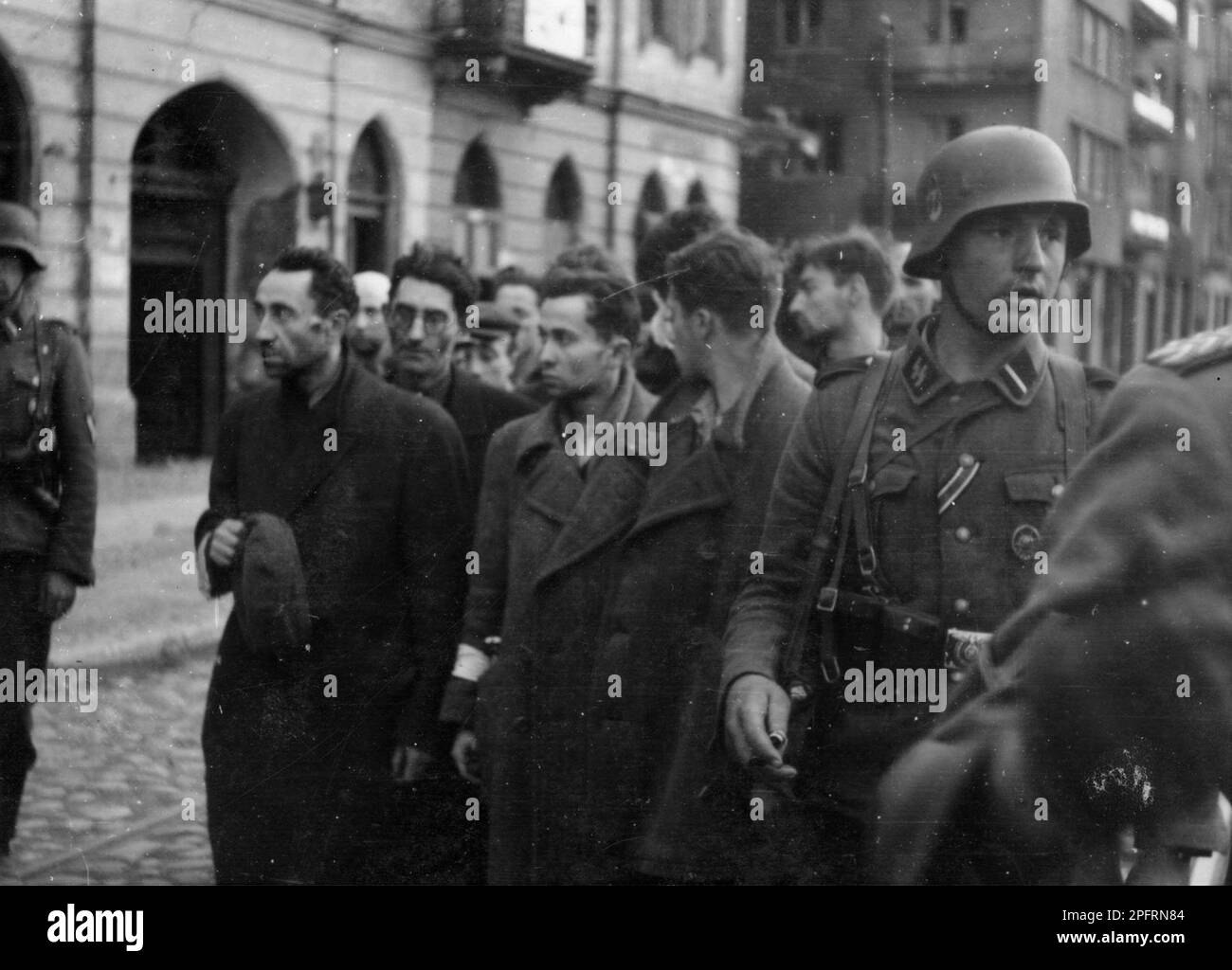 In January 1943 the nazis arrived to round up the Jews of the Warsaw Ghetto  The Jews, resolved to fight it out, took on the SS with homemade and primitive weapons. The defenders were executed or deported and the Ghetto area was systematically demolished. This event is known as The Ghetto Uprising.. This event is kinown as The Ghetto Uprising. This image shows captured fighters under guard in the street. This image is from the German photographic record of the event, known as the Stroop report. Stock Photo