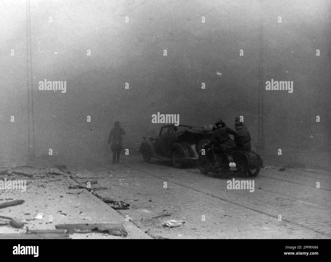 In January 1943 the nazis arrived to round up the Jews of the Warsaw Ghetto  The Jews, resolved to fight it out, took on the SS with homemade and primitive weapons. The defenders were executed or deported and the Ghetto area was systematically demolished. This event is known as The Ghetto Uprising. This image shows a German car and notor bike lost in thick smoke on Zamenhofa Street. This image is from the German photographic record of the event, known as the Stroop report. Stock Photo