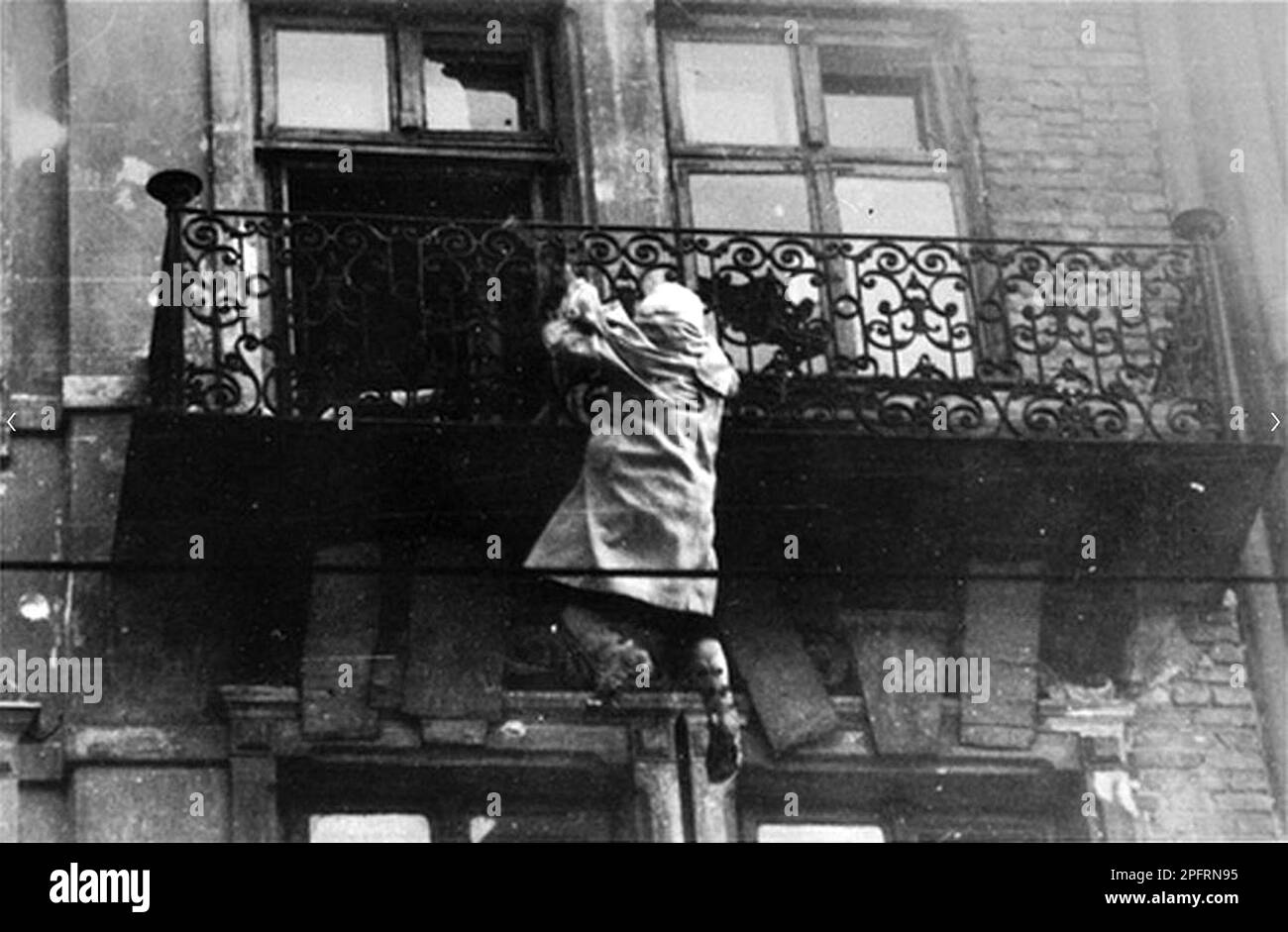 In January 1943 the nazis arrived to round up the Jews of the Warsaw Ghetto  The Jews, resolved to fight it out, took on the SS with homemade and primitive weapons. The defenders were executed or deported and the Ghetto area was systematically demolished. This event is known as The Ghetto Uprising. This image shows a woman hanging from a balcony preparing to drop to the street This image is from the German photographic record of the event, known as the Stroop report. Stock Photo