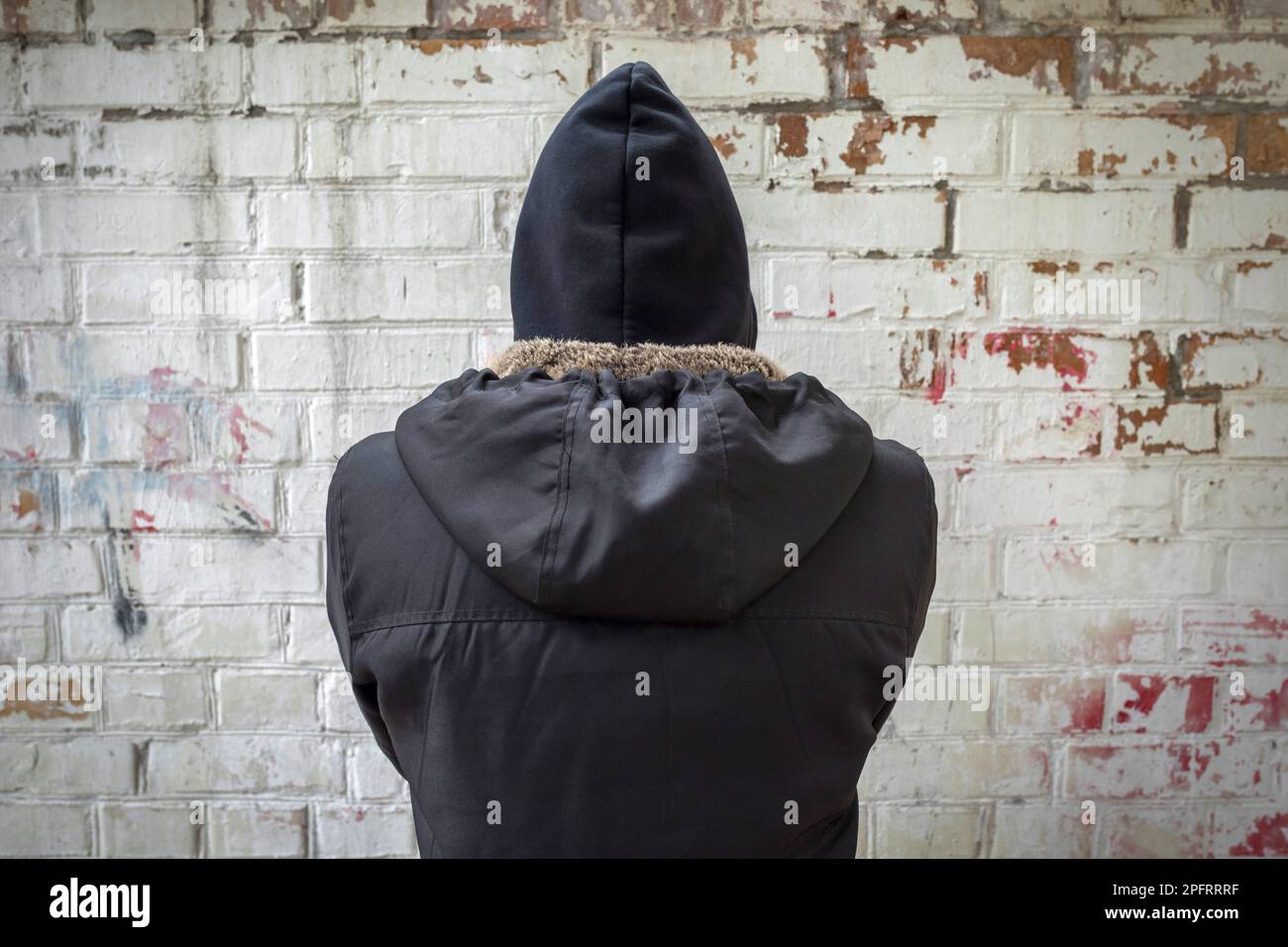 Addict in black on a brick wall background. The view from the back. Man  experiencing a drug addiction crisis. Addiction concept Stock Photo - Alamy