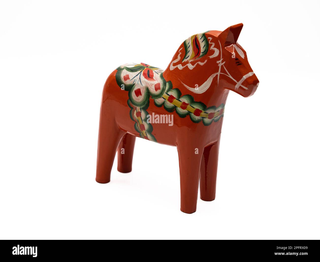 Traditional Swedish Dala Horse (Dalahäst) painted in many colors seen from the side against white background. Stock Photo