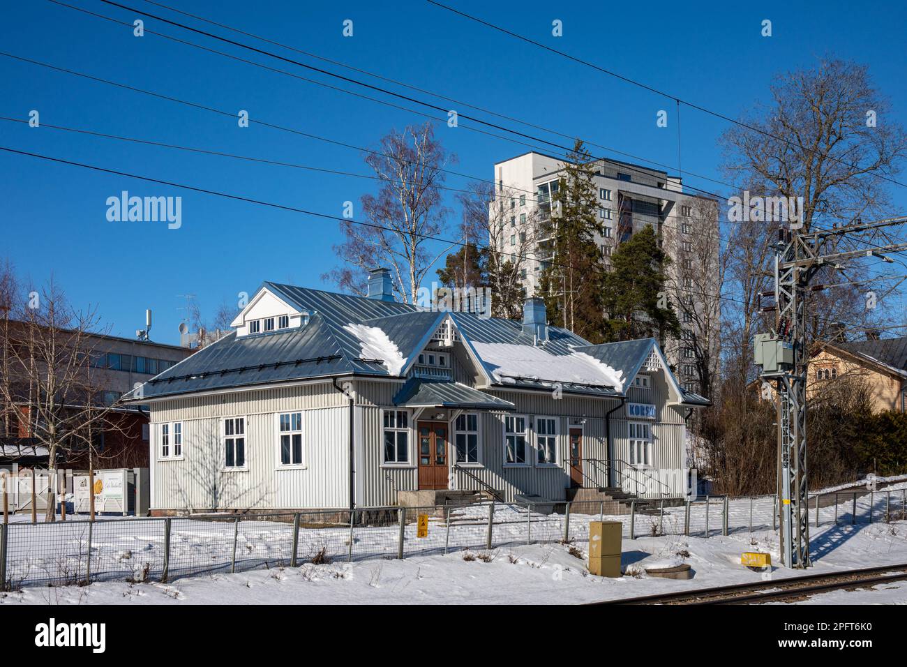 Old wooden building, former railway station, against clear blue sky and a high-rise residential building in Korso district of Vantaa, Finland Stock Photo