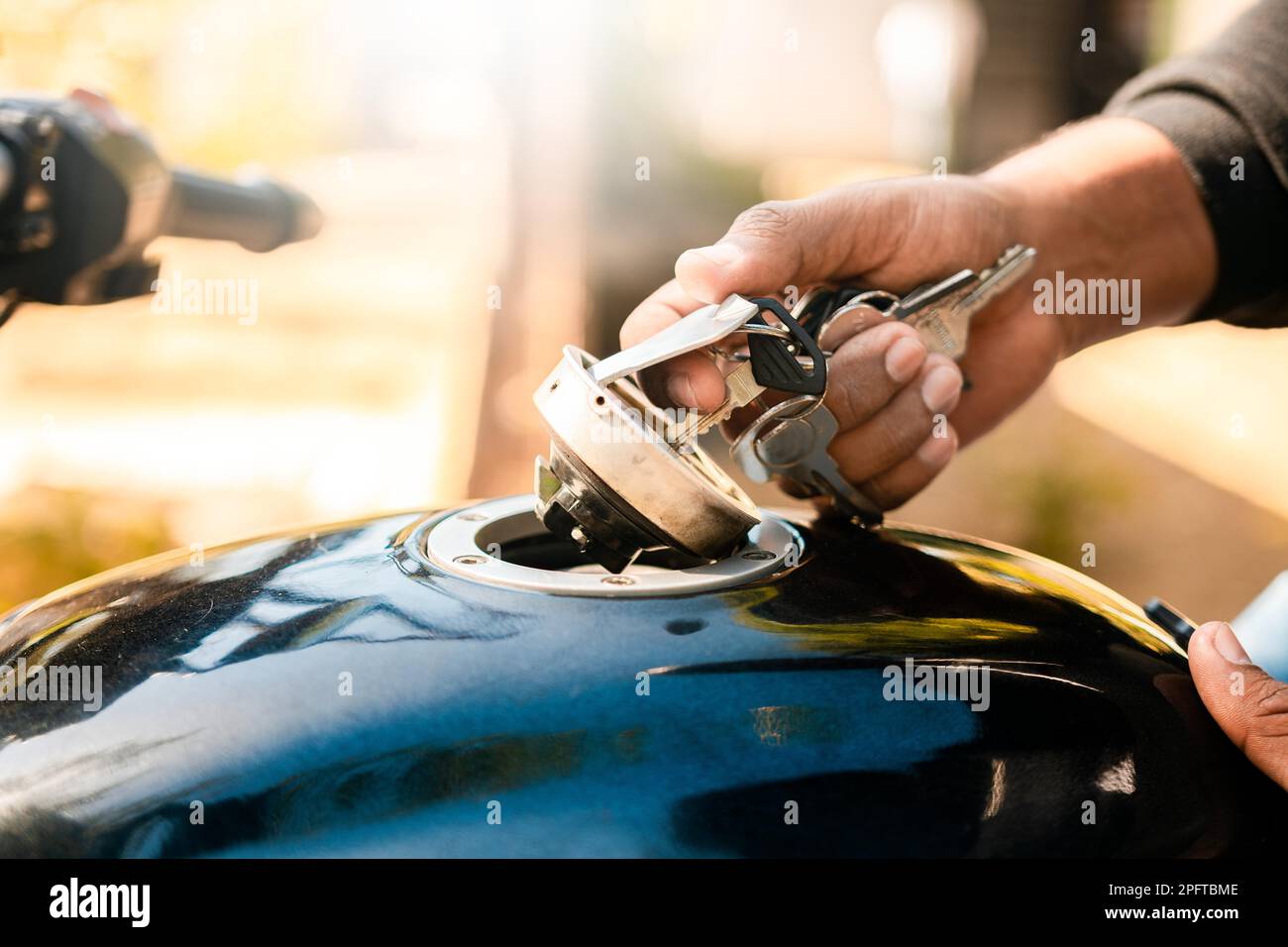 Hands opening the gas tank of the motorcycle with the key. Hand opening the gas tank of the