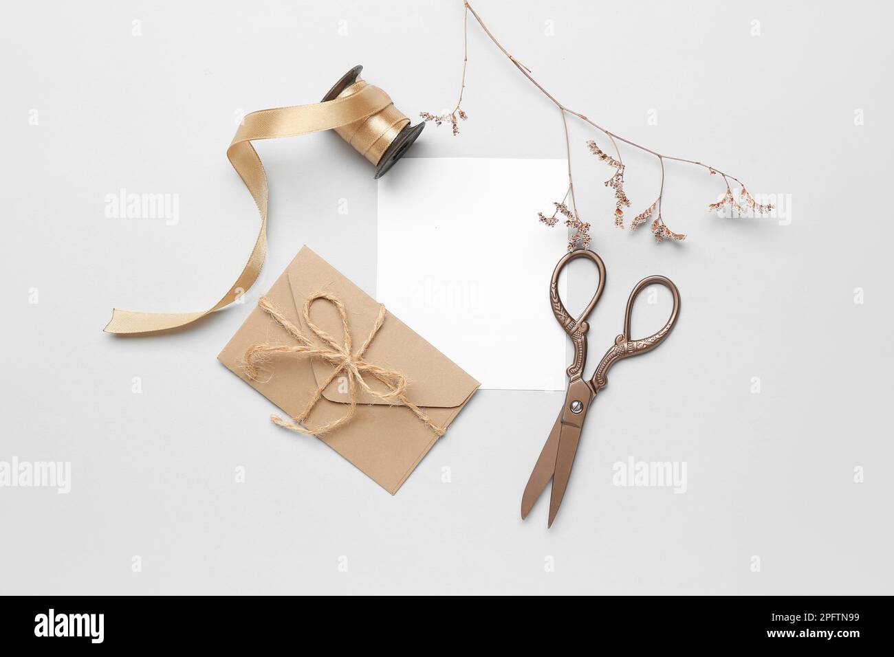 Composition with blank card, envelope, ribbon and scissors on white ...