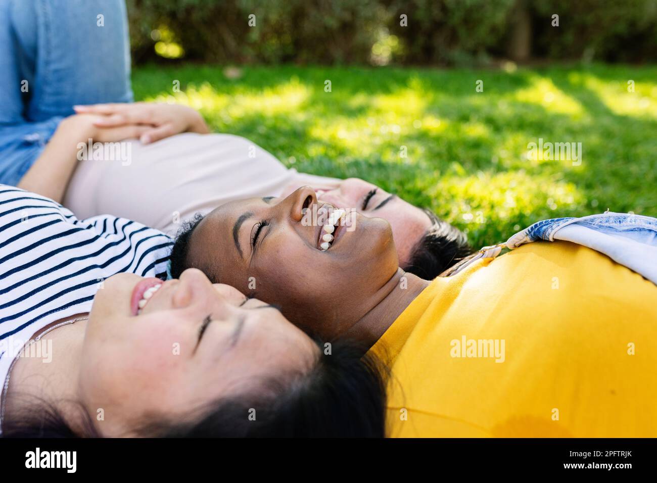 Three diverse young women friends laughing together outdoors Stock ...