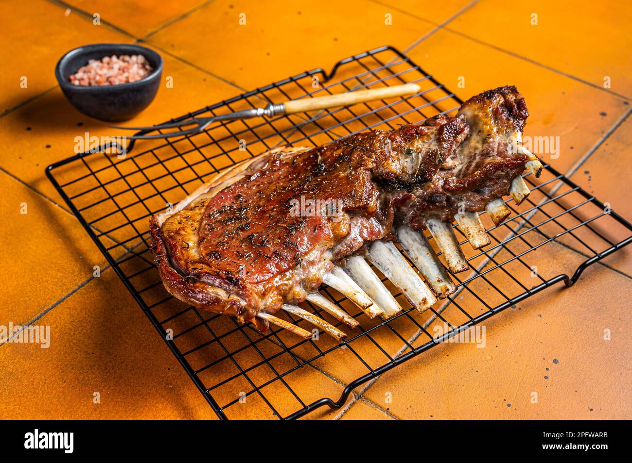 Roast Rack of lamb ribs, spareribs on grill. Orange background. Top ...