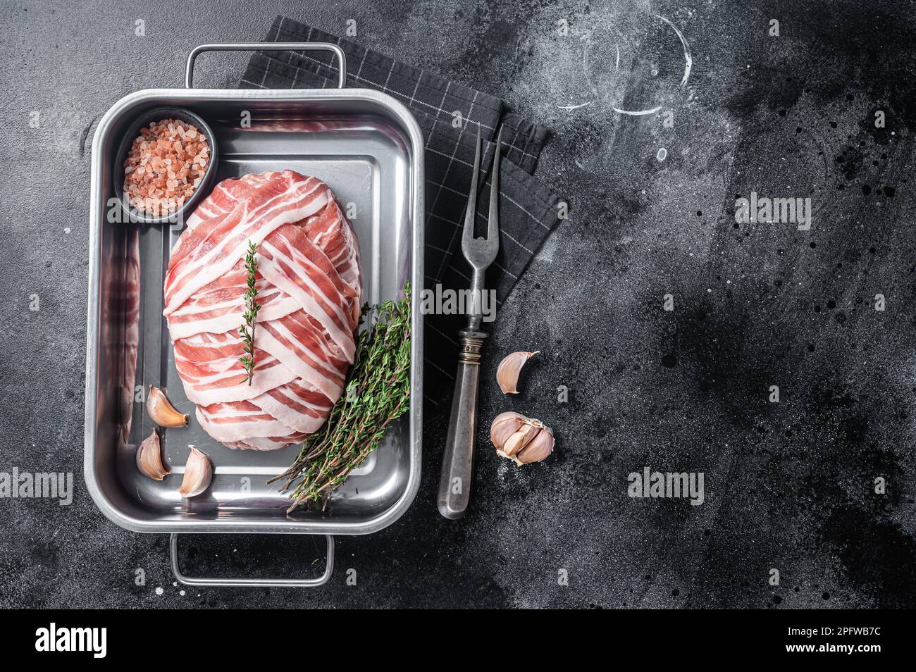 Cooking raw meatloaf with ground beef meat and bacon in steel tray