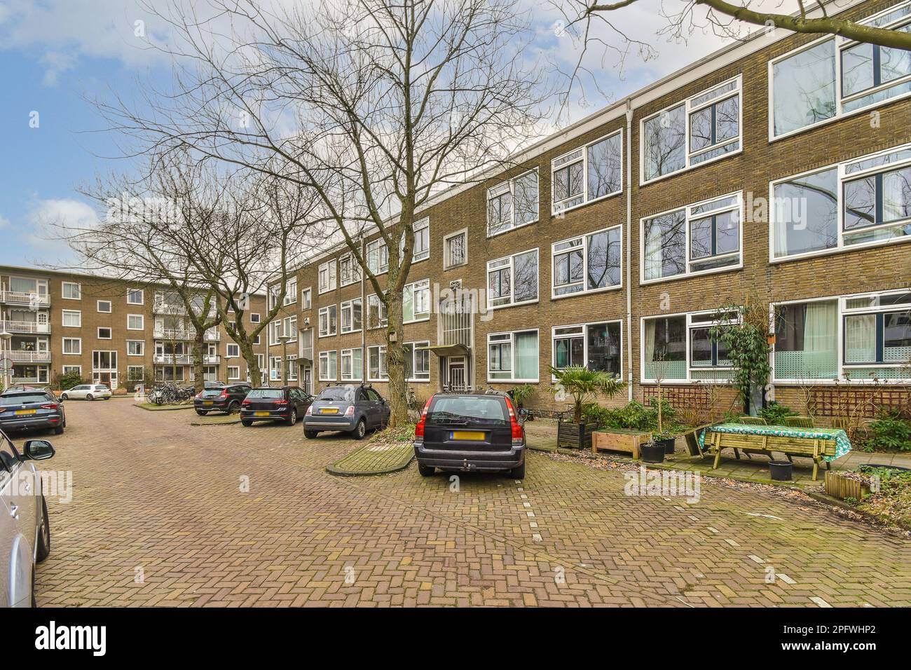 a street with cars parked on the side and trees in the back ground next ...