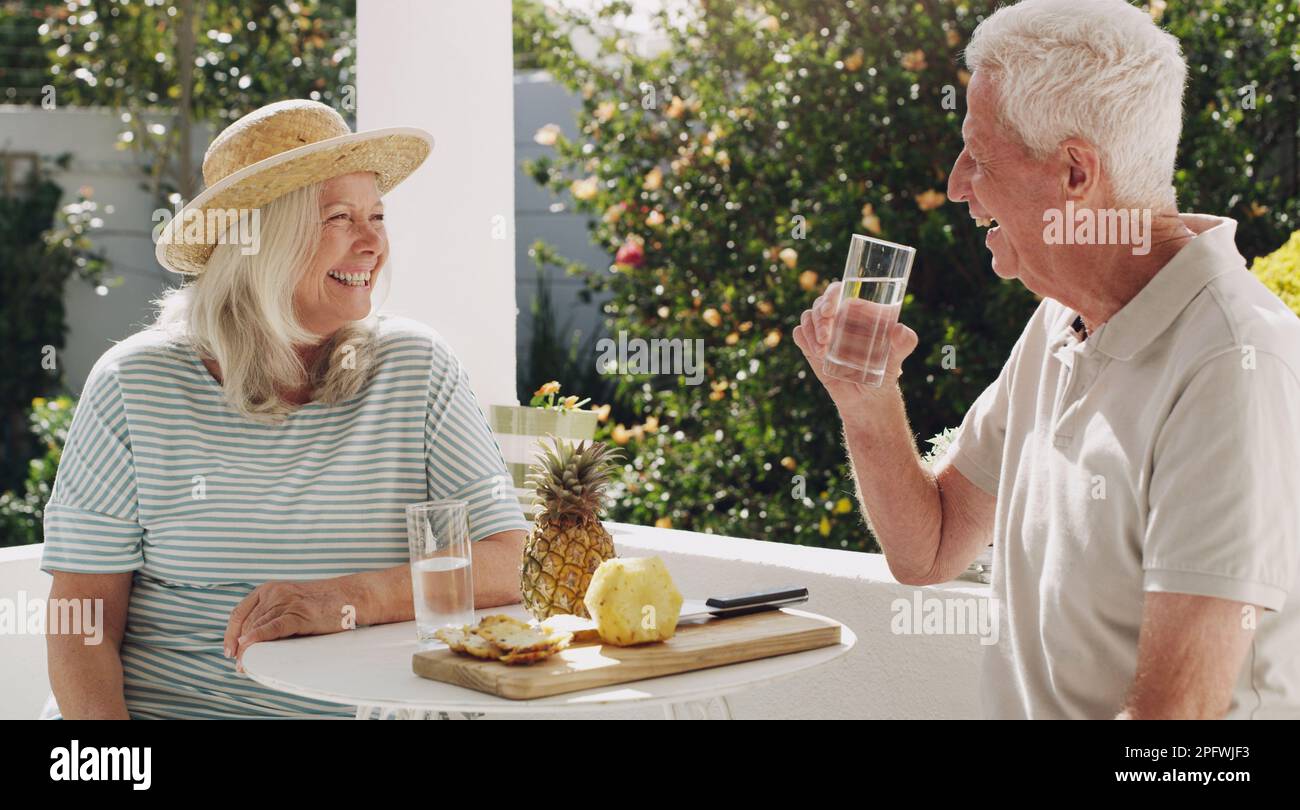 We always find something to giggle about. a happy senior couple sitting outside together and enjoying a snack. Stock Photo
