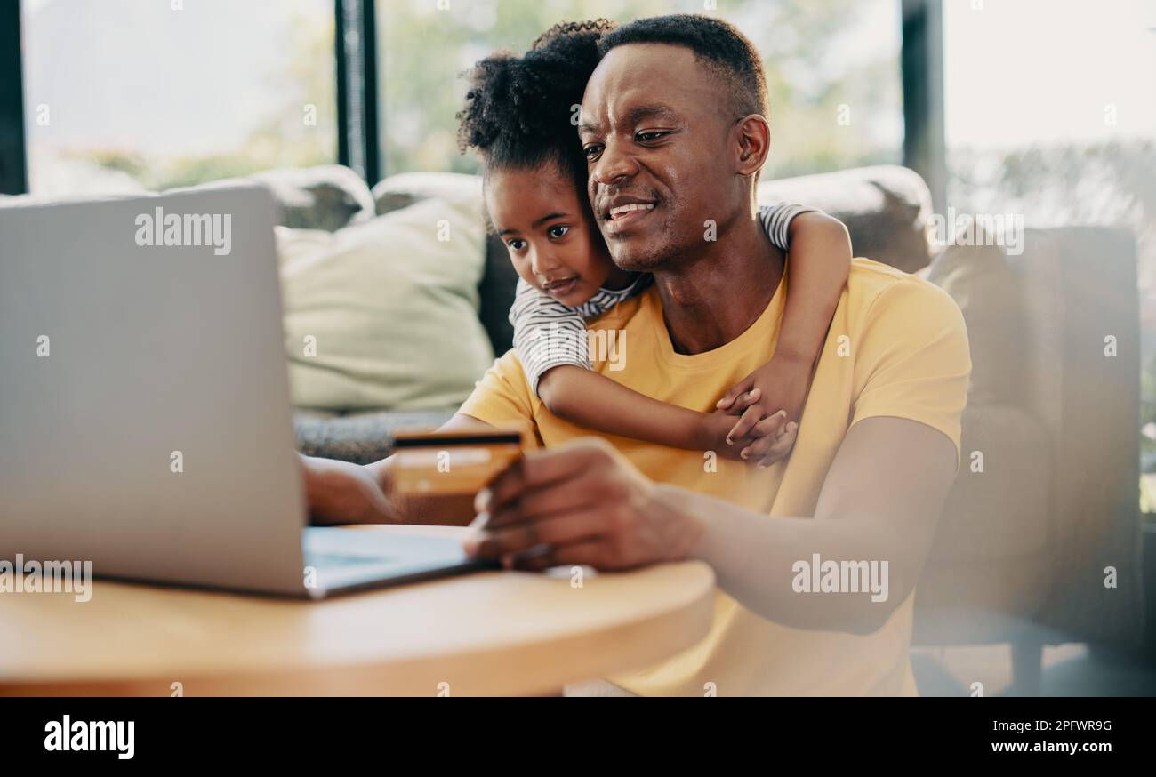 Online shopping and ecommerce, father and daughter buying some things online with a credit card. Man and his daughter browse an online shop on a lapto Stock Photo