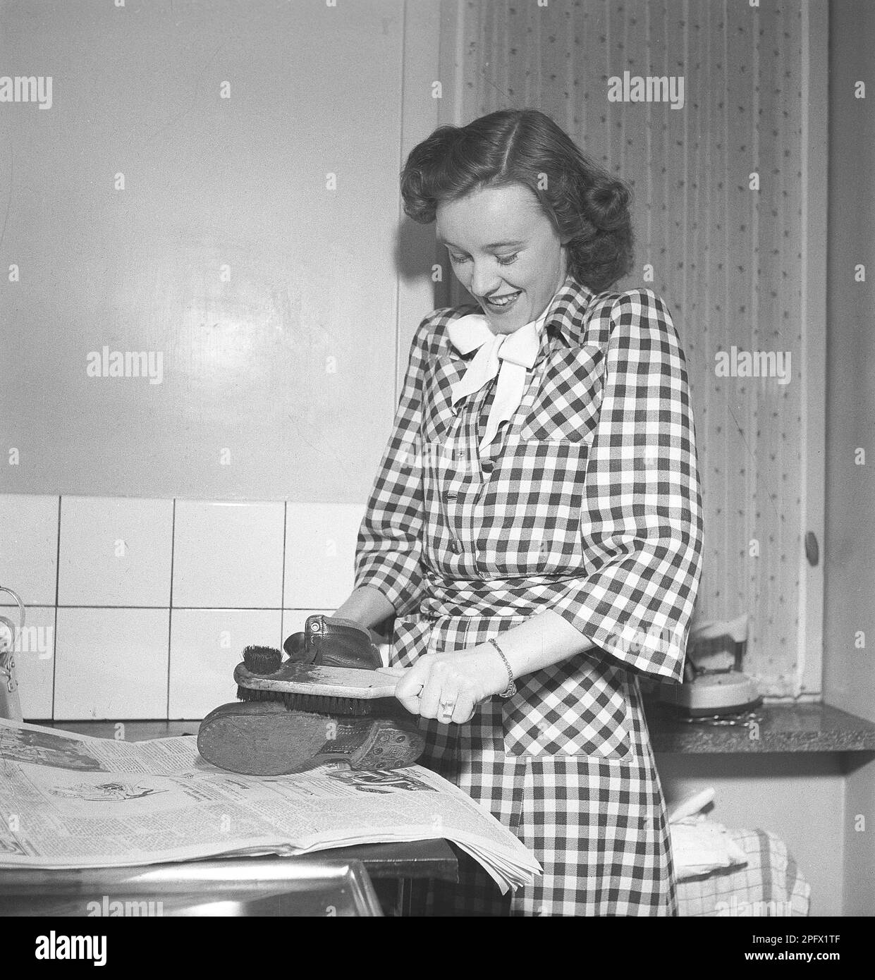 Shoes in the 1940s. A young woman polishes a shoe with a shoe brush. The leather shoe that is worn will have it's dirt removed and shine of the shoe polish Sweden 1946 Kristoffersson ref Z20-5 Stock Photo