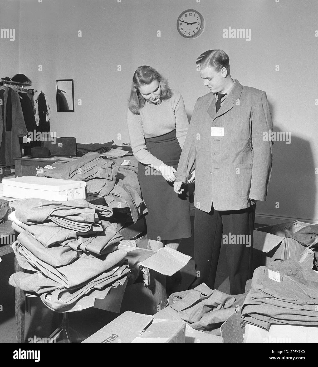 A young man tries on a jacket that is too big and is helped by a young