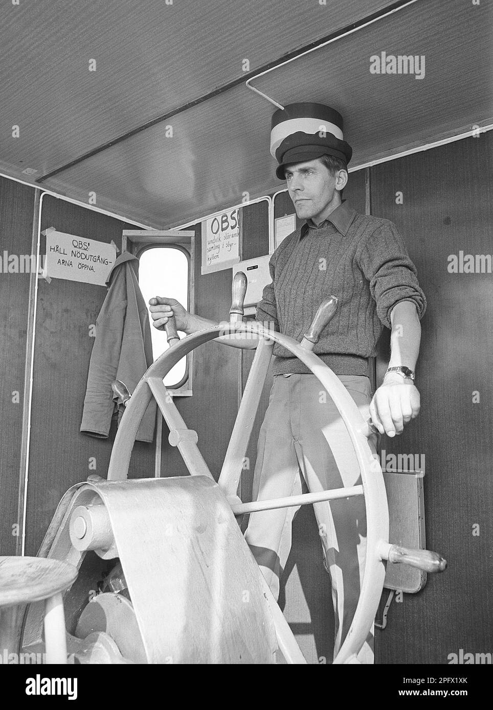 At the rudder. A man at the rudder steer the ship on course, he looks focused on what's ahead.     Sweden 1970 ref ED1 Stock Photo