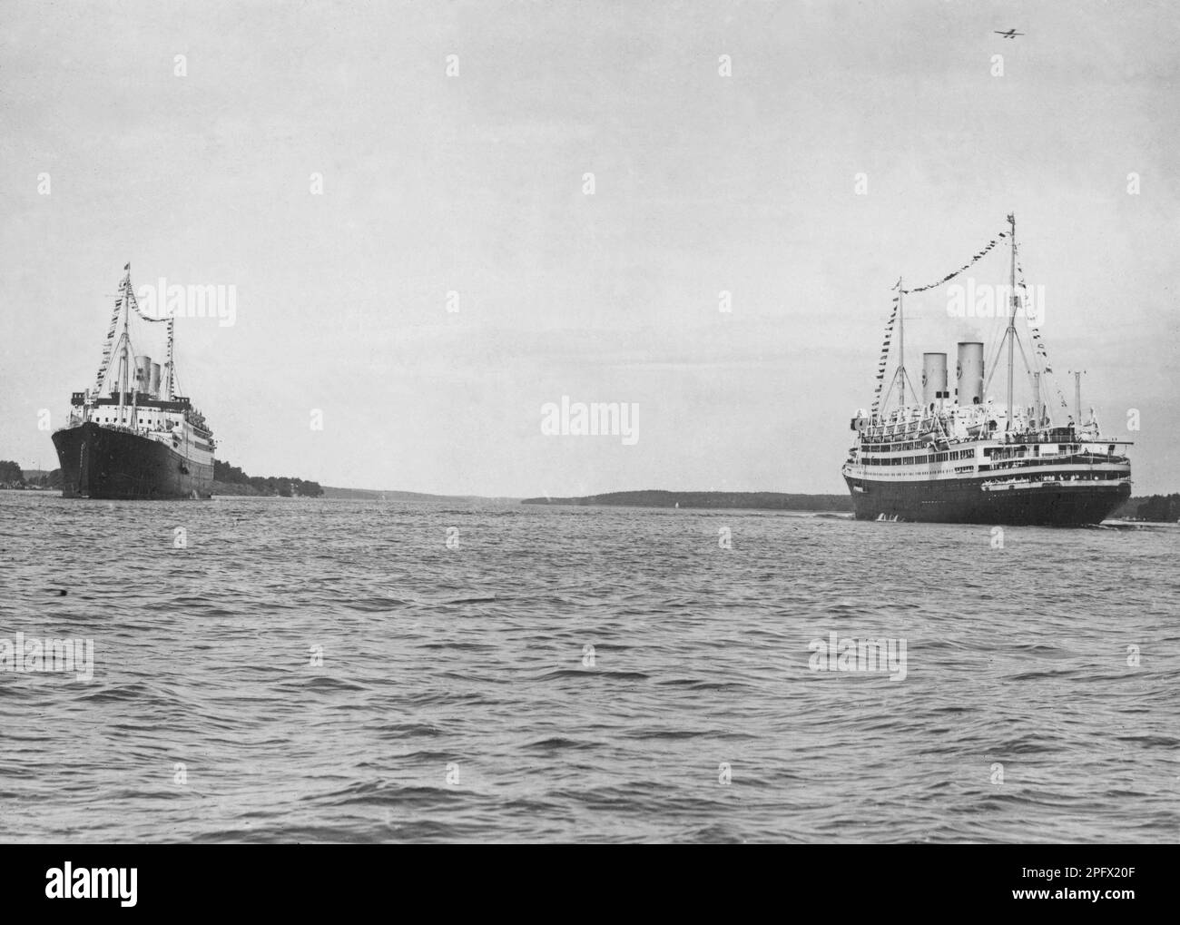 Svenska Amerika Linien's ships M/S Kungsholm and M/S Gripsholm meet in the Stockholm archipelago in July 1930. The ships built in the 1920s were sister ships and the most modern ships on the Atlantic at the time. Gripsholms with a length of 168.5 meters and a width of 22.7 meters and Kungsholm, which was 181.32 and 22 meters wide, were veritable floating luxury palaces and celebrities of the time traveled on them. Both ships ended their days as scrap. Stock Photo