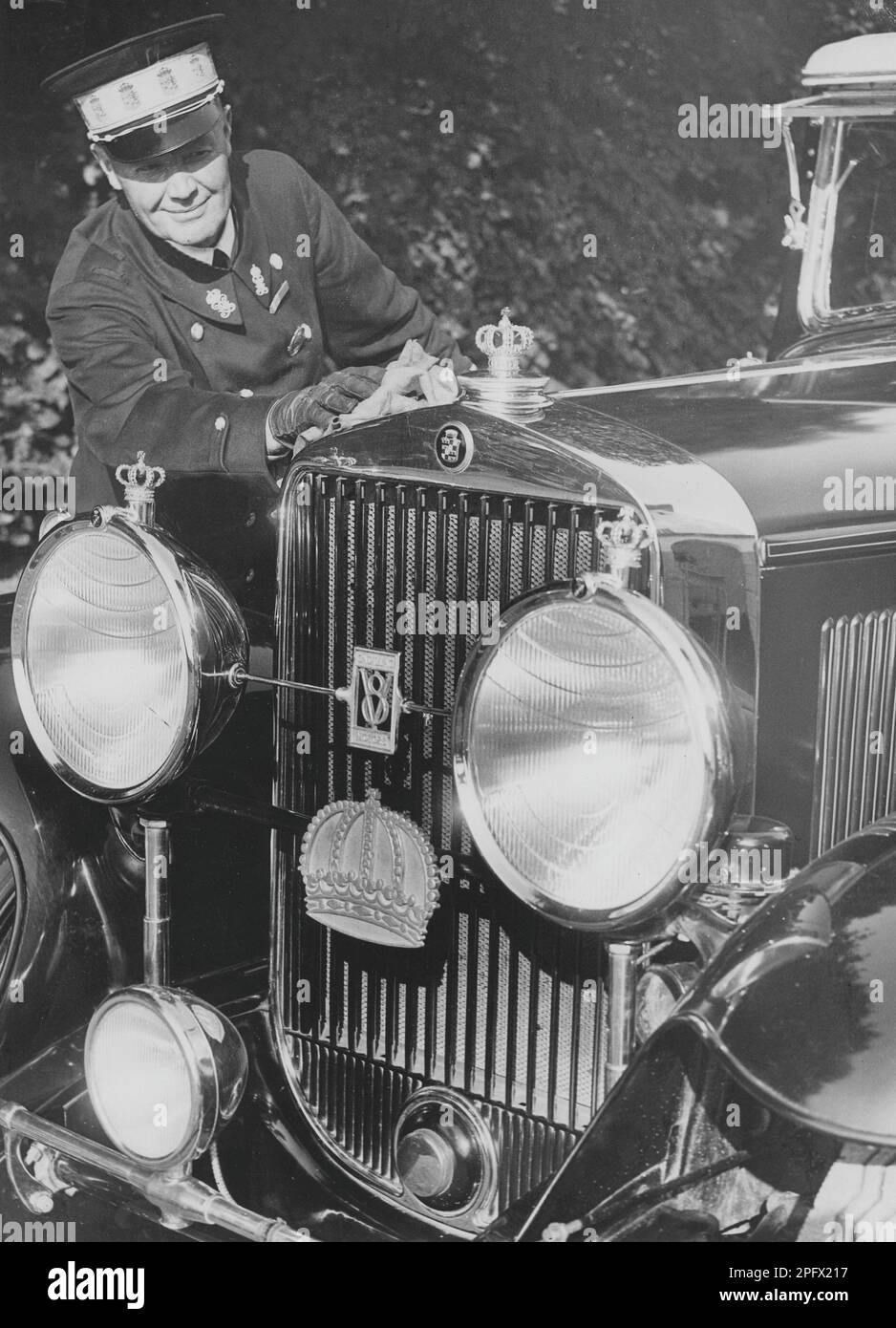 A royal chauffeur polishes the royal Cadillac. The decoration in the form of small crowns on the hood, on the lights and on the grill leaves no doubt as to who the car belongs to. Sweden 1940s Stock Photo