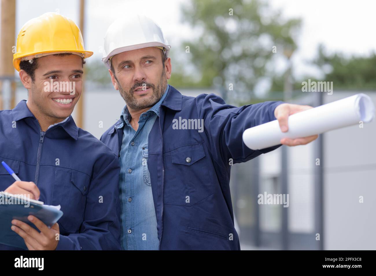 builders in helmets pointing outdoors Stock Photo