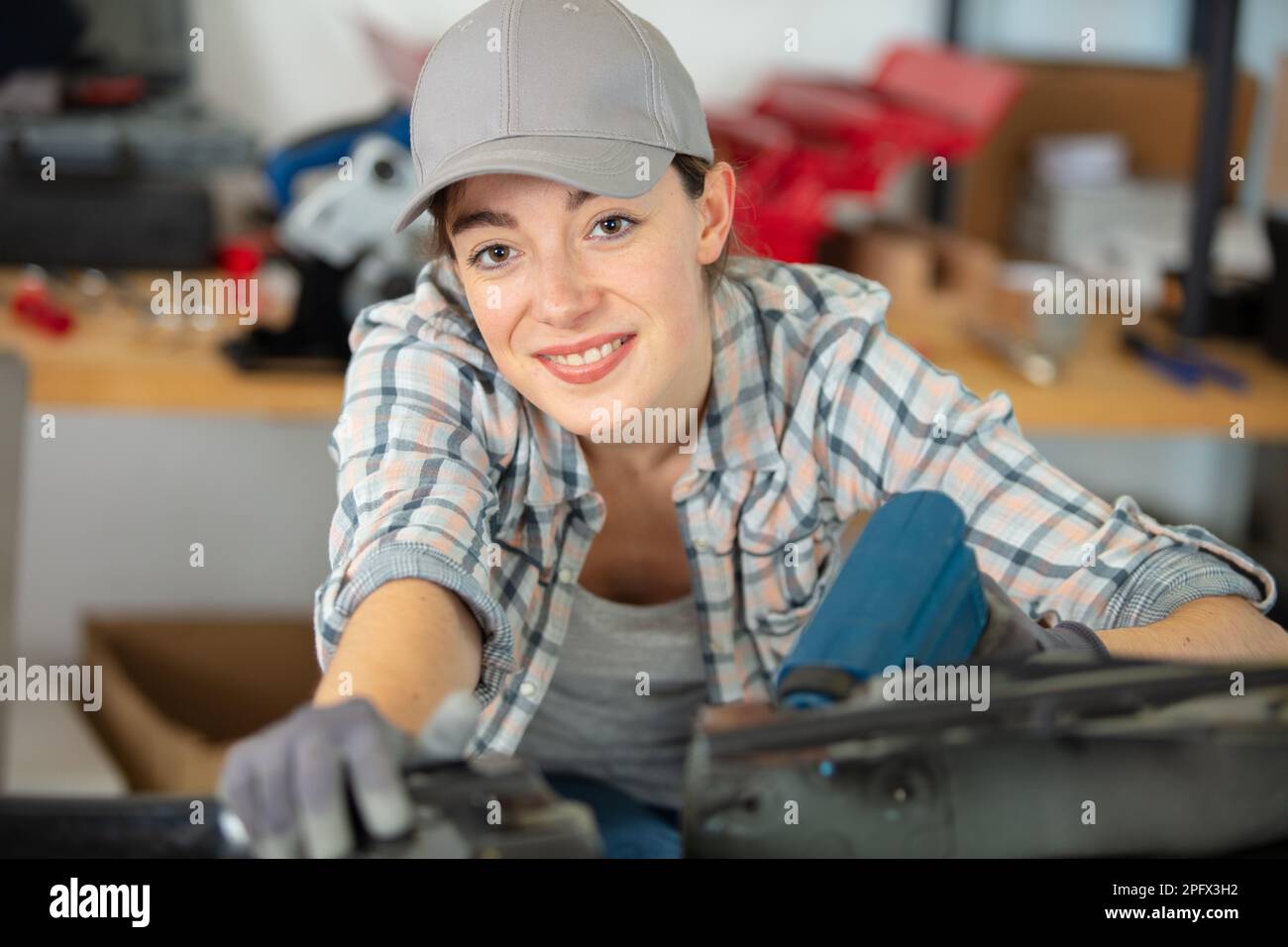 female mechanic uses power tool in the workshop Stock Photo - Alamy