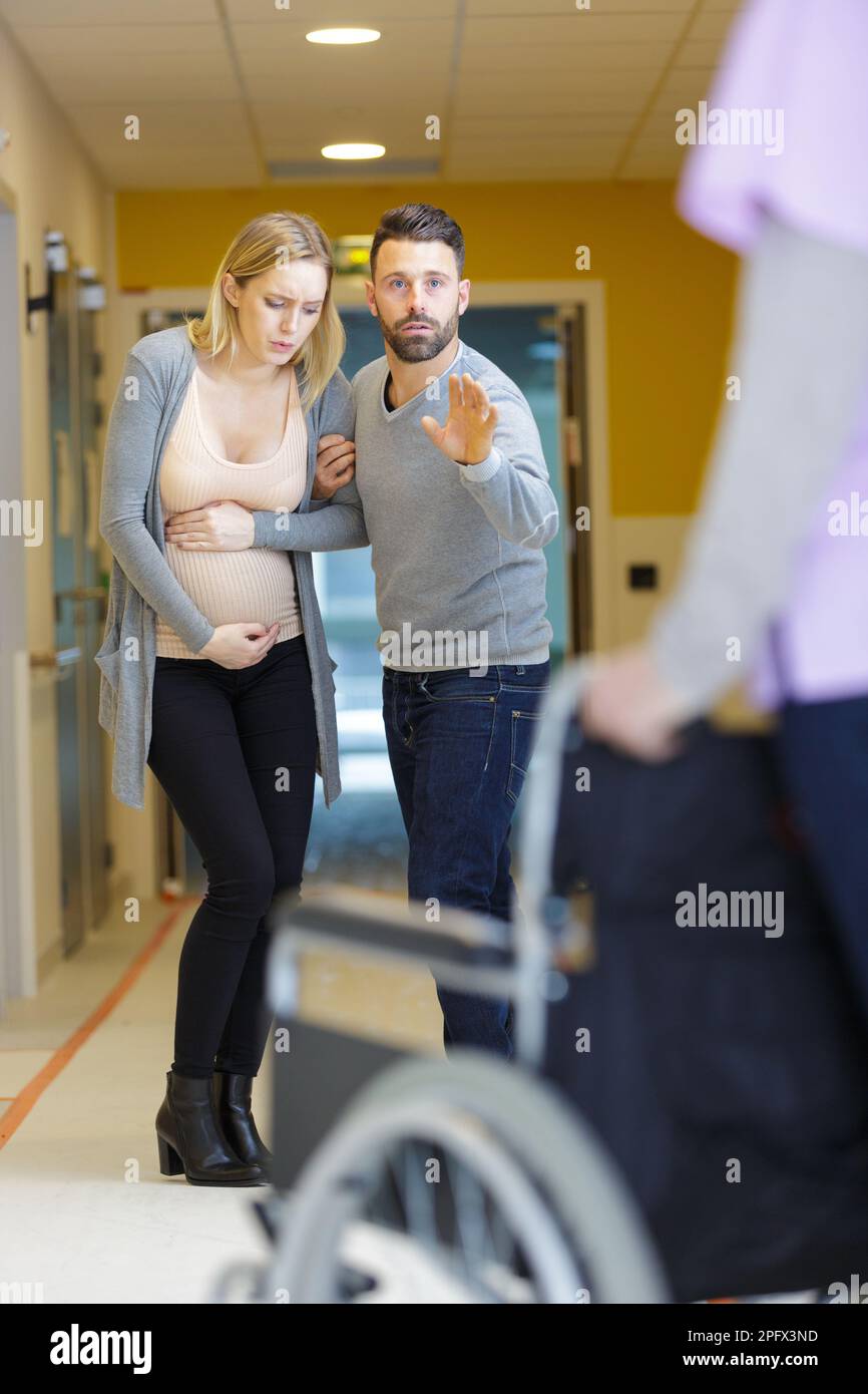man helping pregnant partner in hospital corridor Stock Photo