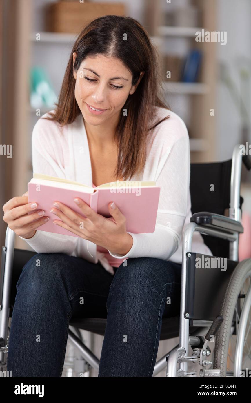 happy disabled handicapped woman sit on wheelchair holding book Stock