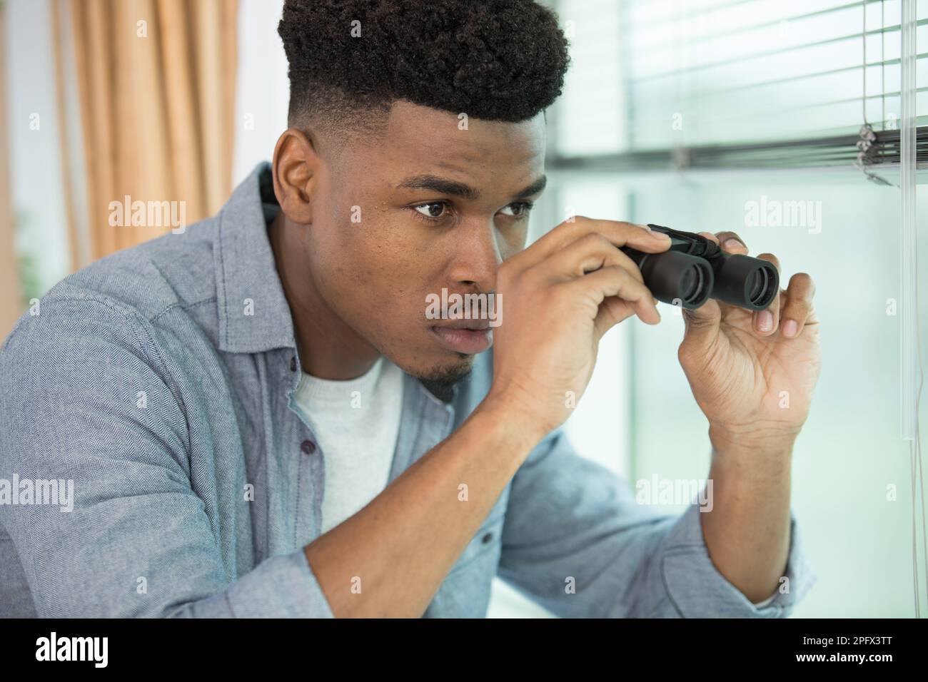 handsome man with binoculars on grey background Stock Photo
