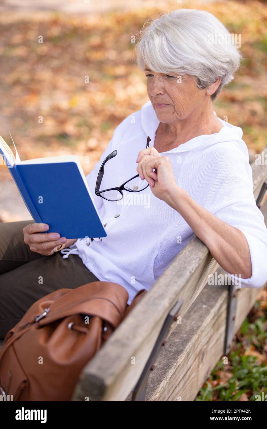 senior woman reading a book on the bench Stock Photo - Alamy