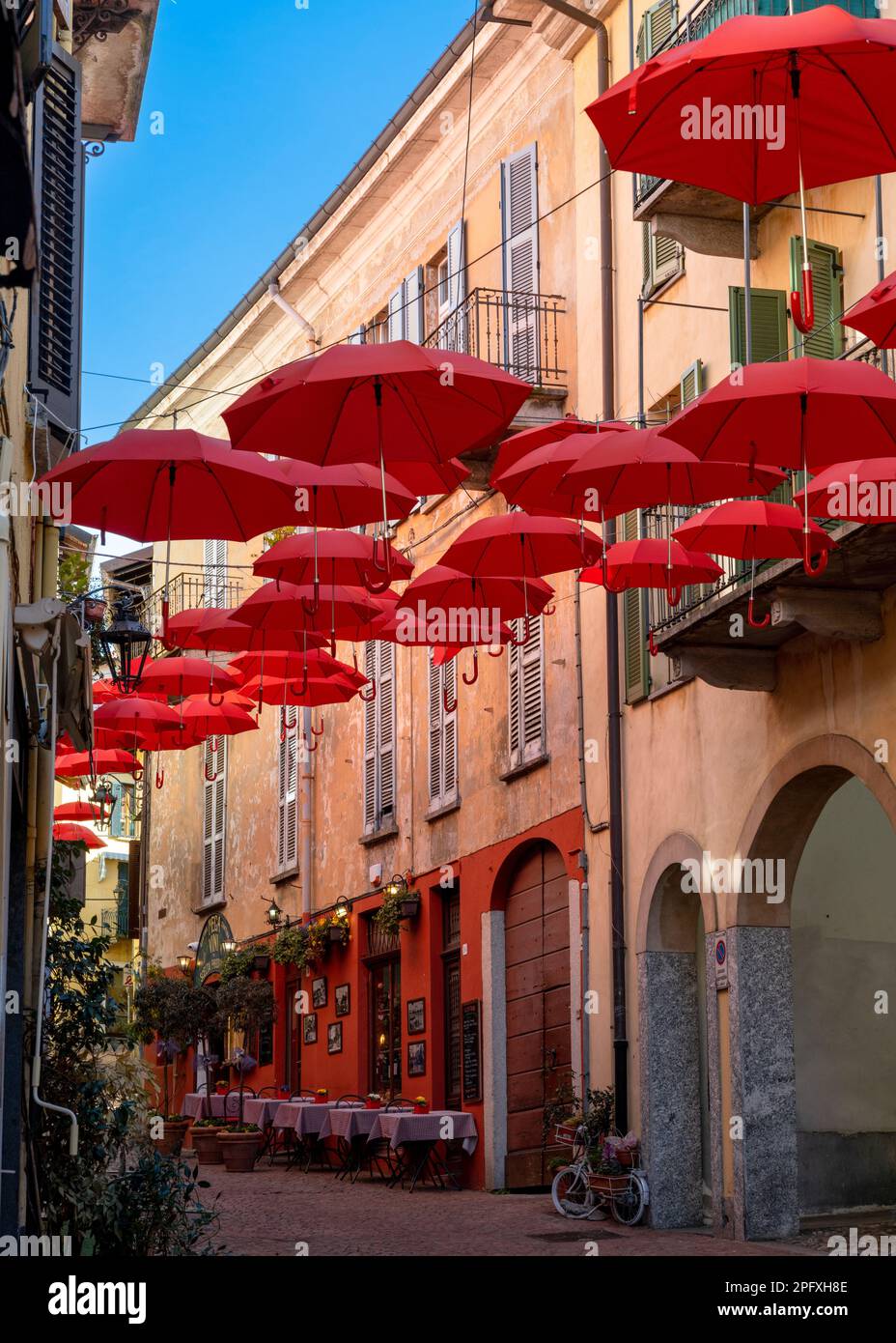 Luino, Italy - 16 March, 2023: vertical view of a cobblestone street with small shops and colorful decorations in the old city center of Luino Stock Photo