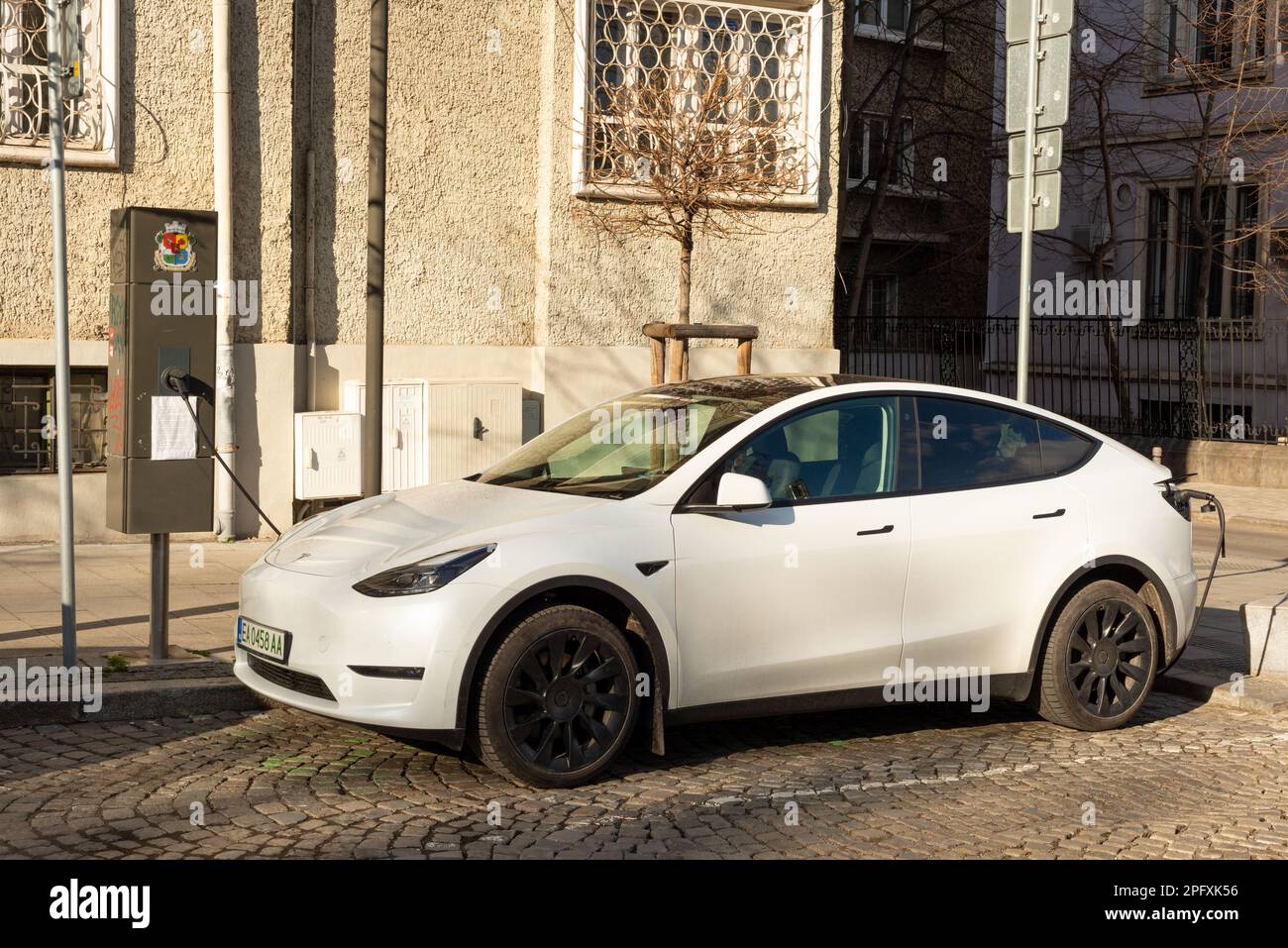 White Tesla Y electric car being charged at a small local neighbourhood street EV charging station in Sofia, Bulgaria, Eastern Europe, Balkans, EU Stock Photo