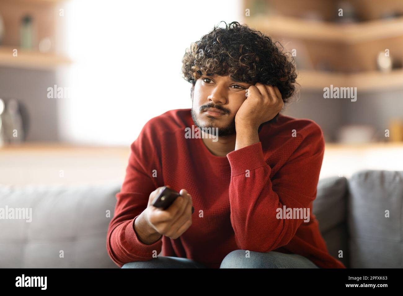 Boring Program. Portrait Of Upset Young Indian Man Watching TV At Home Stock Photo