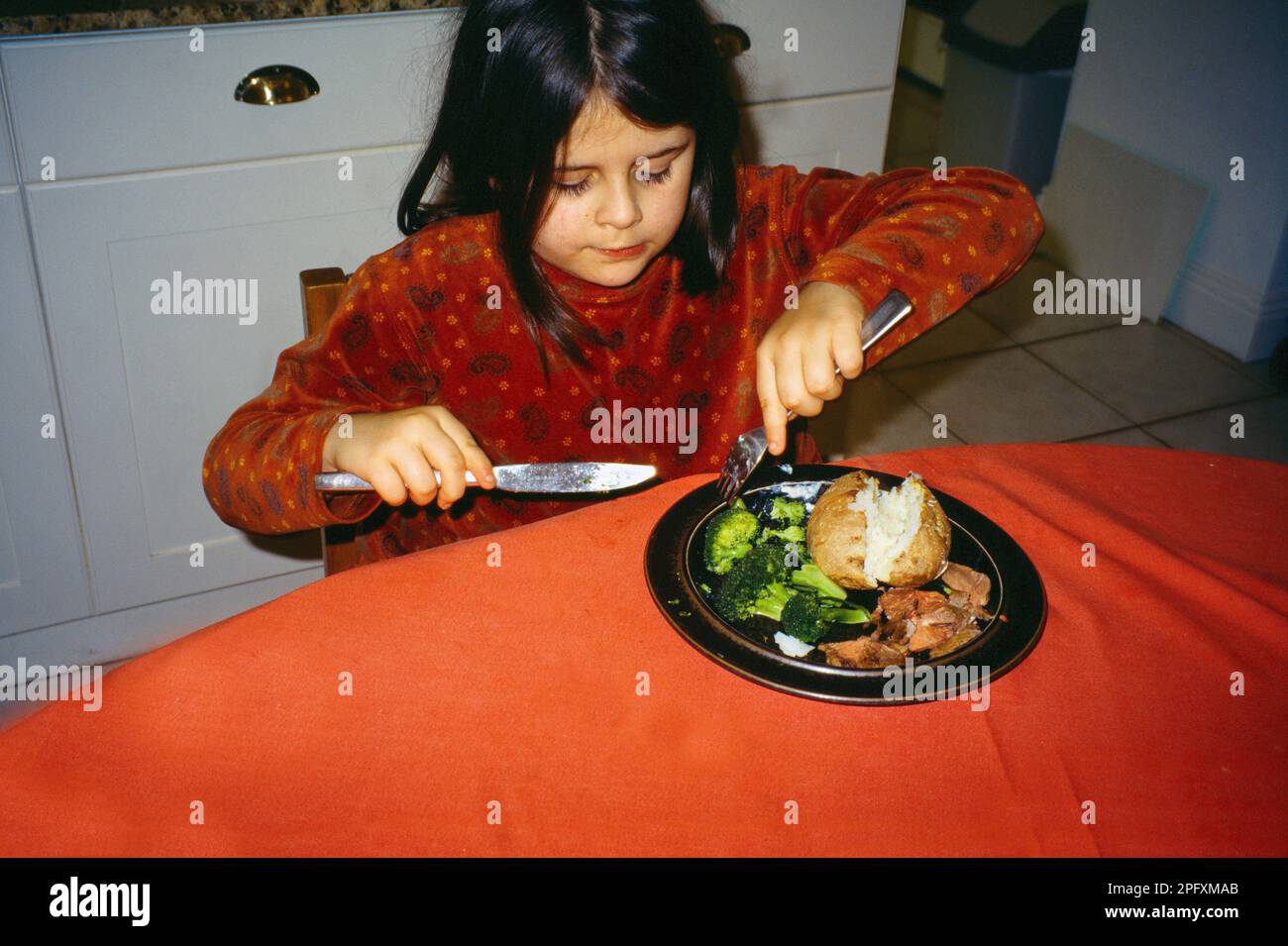 Child Eating Broccoli with Jacket Potato for Dinner Surrey England