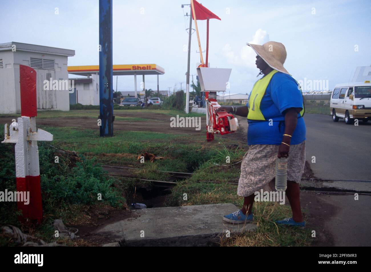 Basseterre St Kitts Large Woman Wearing Fluorescent Vest holding a Bottle of Water walking by Railway Lines Stock Photo