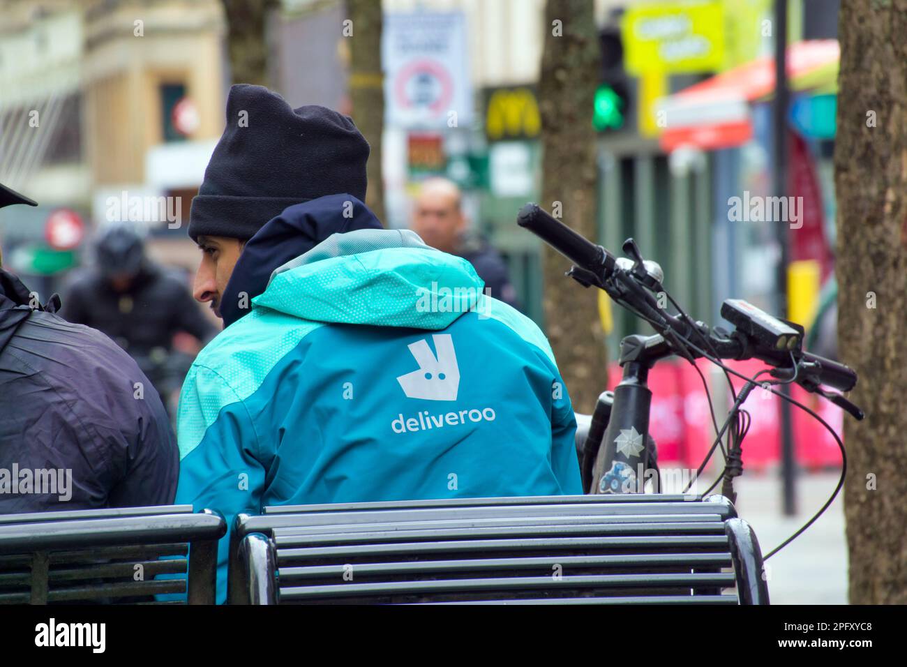 Glasgow, Scotland, UK 19th March, 2023. UK Weather: Deliveroo drier sitting firing a breakSunny in the city centre afternoon saw the city locals take to the streets. Sauchiehall street was busy.Credit Gerard Ferry/Alamy Live News Stock Photo