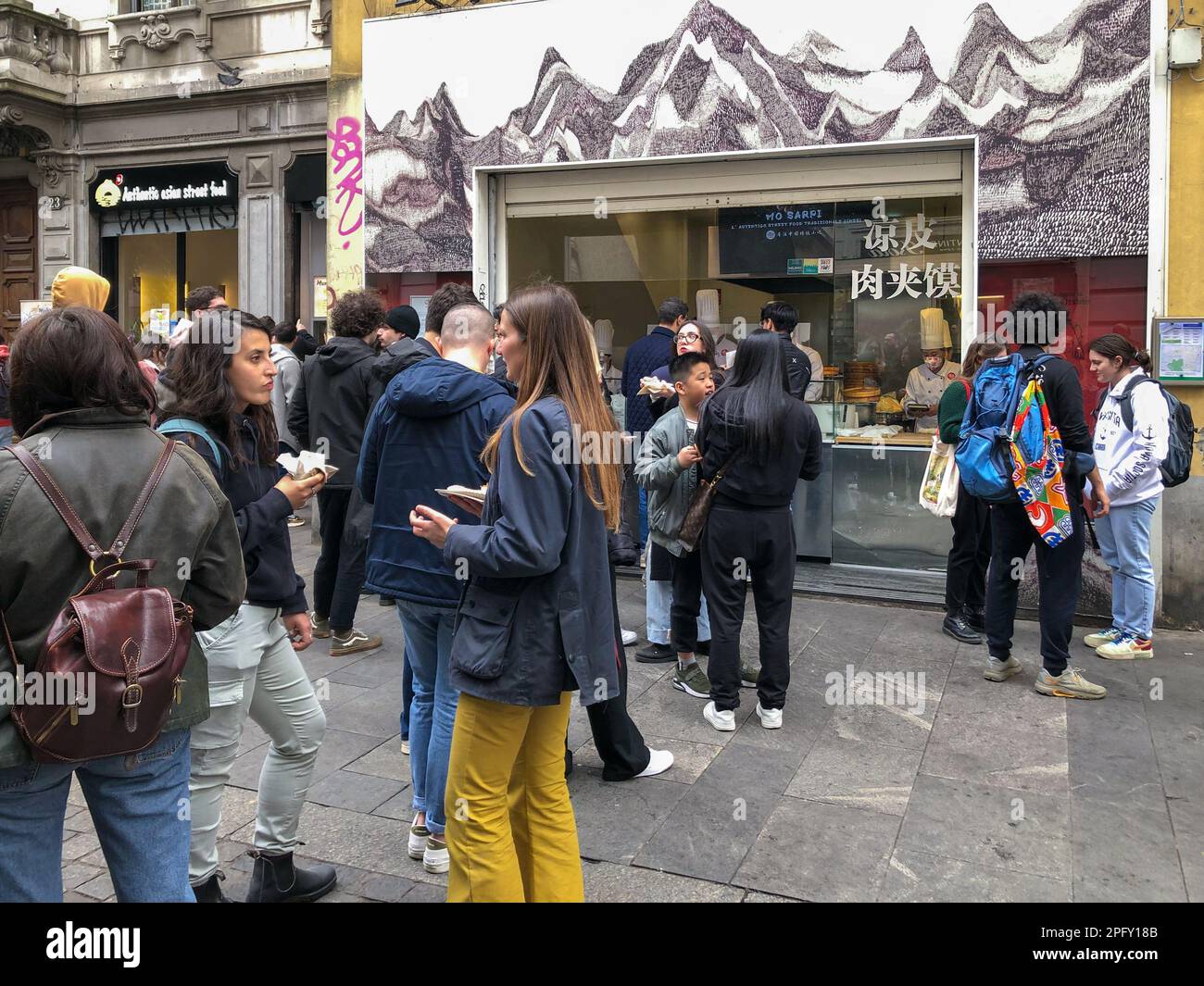 People in front of a Chinese take away restaurant in Milan's Chinatown