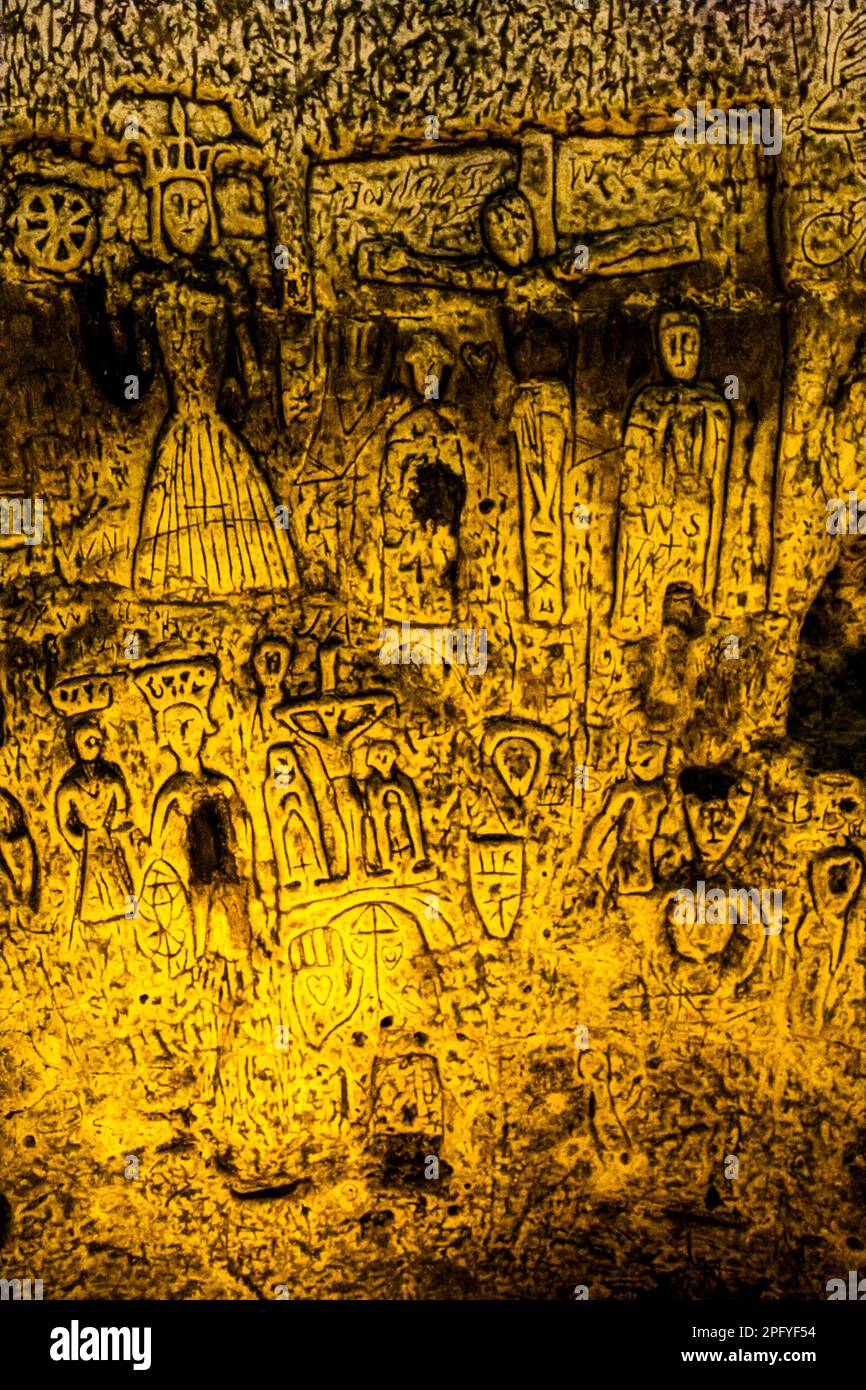 Royston Cave in Herfordshire U.K. still puzzles historians today. The cave is decorated with a large number of low-relief wall sculptures. They are mainly Christian motifs in the medieval style. St. Catherine with the Breaking Wheel is one of the larger Christian carvings in Royston Cave in Katherine's Yard, Melbourn Street, Royston, England Stock Photo