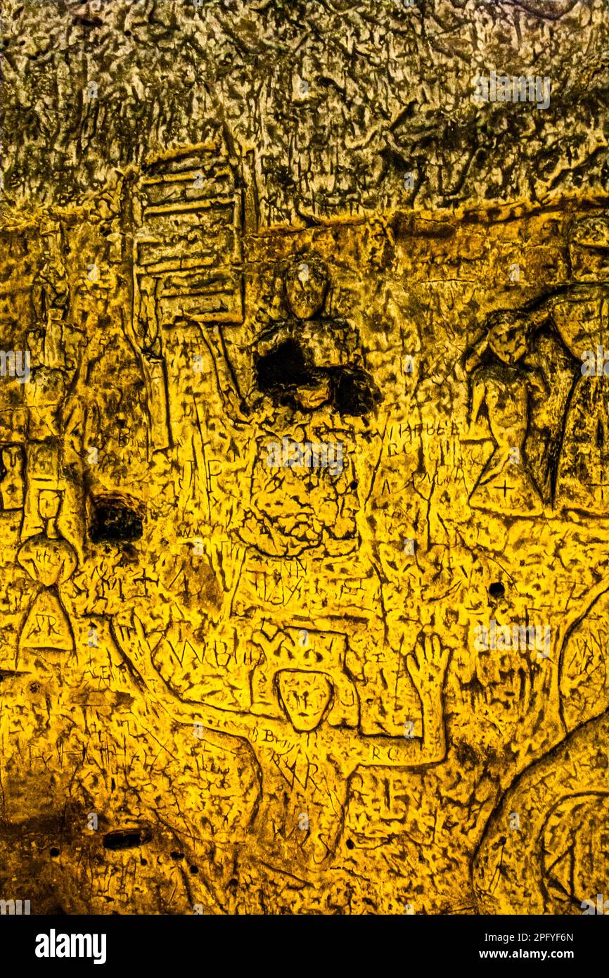 Royston Cave in Herfordshire U.K. still puzzles historians today. The cave is decorated with a large number of low-relief wall sculptures. They are mainly Christian motifs in the medieval style. The dark figure: St Lawrence who was martyred on a gridiron. Royston Cave in Katherine's Yard, Melbourn Street, Royston, England Stock Photo