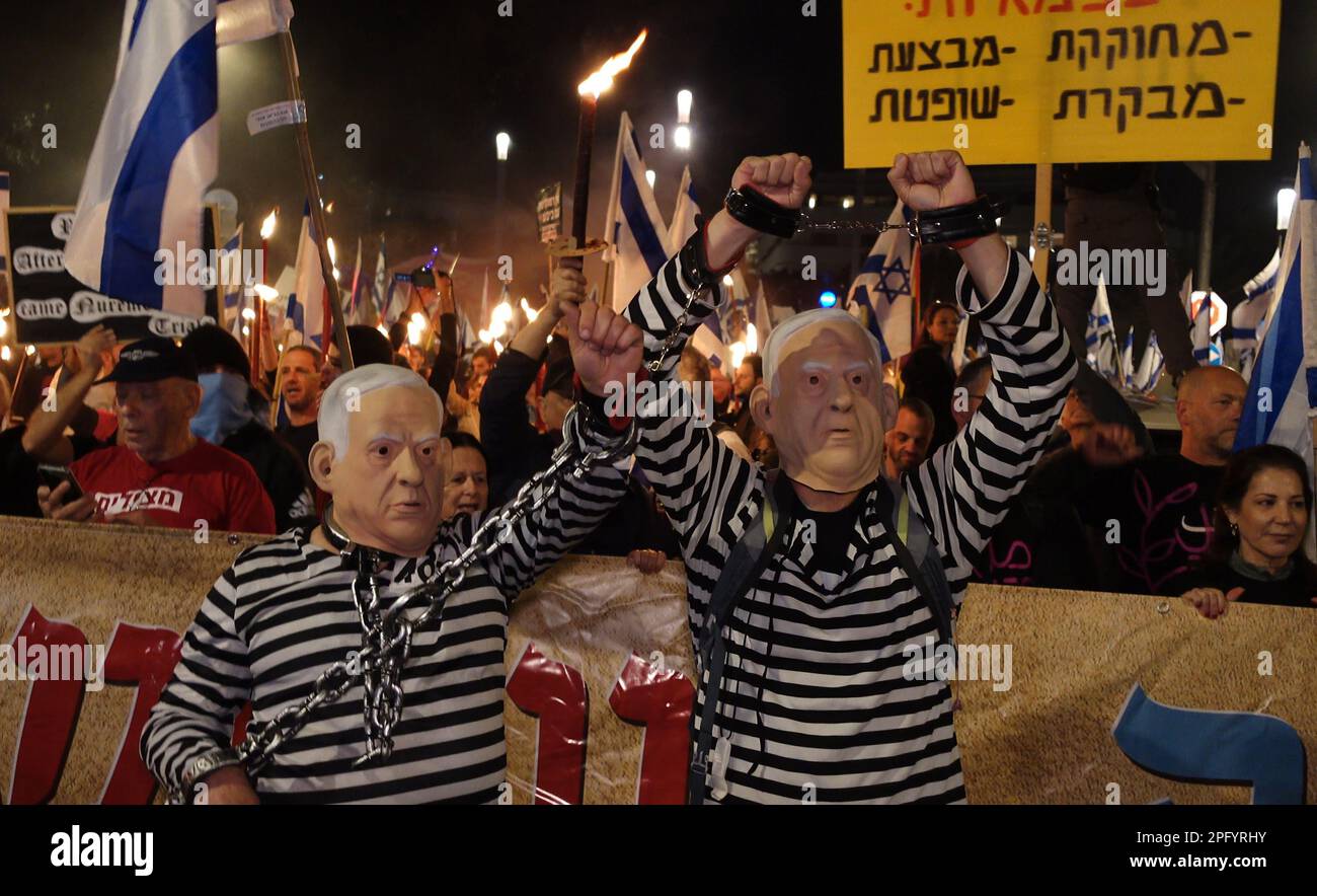 TEL AVIV, ISRAEL - MARCH 18: Anti-government protestors wear masks with the effigy of Prime Minister-Benjamin Netanyahu in a prison uniform and shackled hands as others chant slogans during a mass demonstration for the 11th consecutive week against Israel's hard-right government judicial system plan that aims to weaken the country's Supreme Court on March 18, 2023 in Tel Aviv, Israel. Credit: Eddie Gerald/Alamy Live News Stock Photo