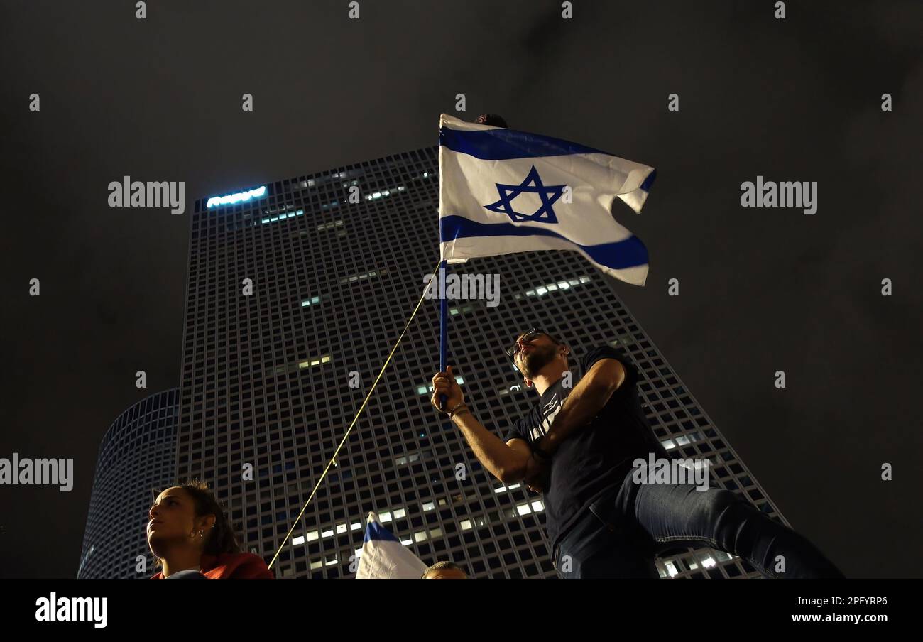 TEL AVIV, ISRAEL - MARCH 18: Anti-government protestors hold Israeli flags during a mass demonstration for the 11th consecutive week against Israel's hard-right government judicial system plan that aims to weaken the country's Supreme Court on March 18, 2023 in Tel Aviv, Israel. Credit: Eddie Gerald/Alamy Live News Stock Photo
