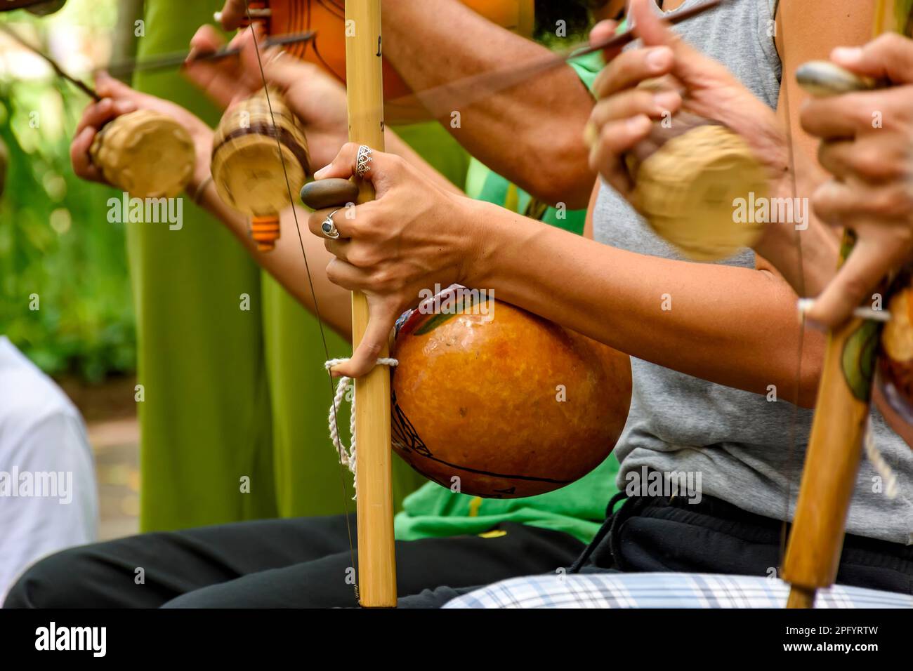 Several musicians playing an Afro Brazilian percussion musical instrument called the berimbau during a capoeira performance in the streets of Brazil Stock Photo