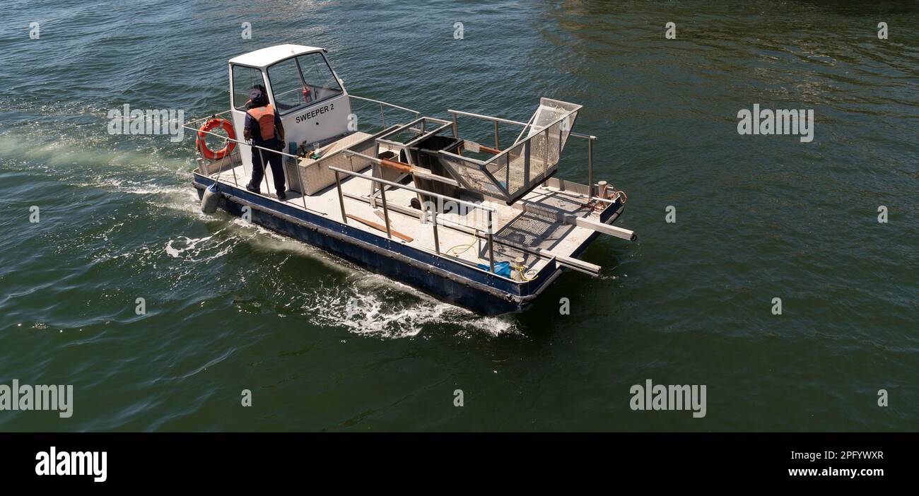 Cape Town, South Africa. 2023. Overview of a sweeper boat and crew underway to clean the habour water of rubbish Stock Photo