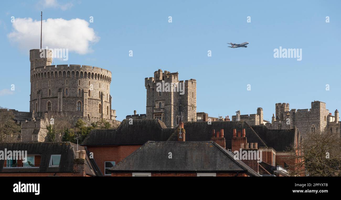 Windsor, Berkshire, England, UK. 2023.  Windsor Castle viewed with a four engined passenger jet inflight close by having taken off from London Heathro Stock Photo