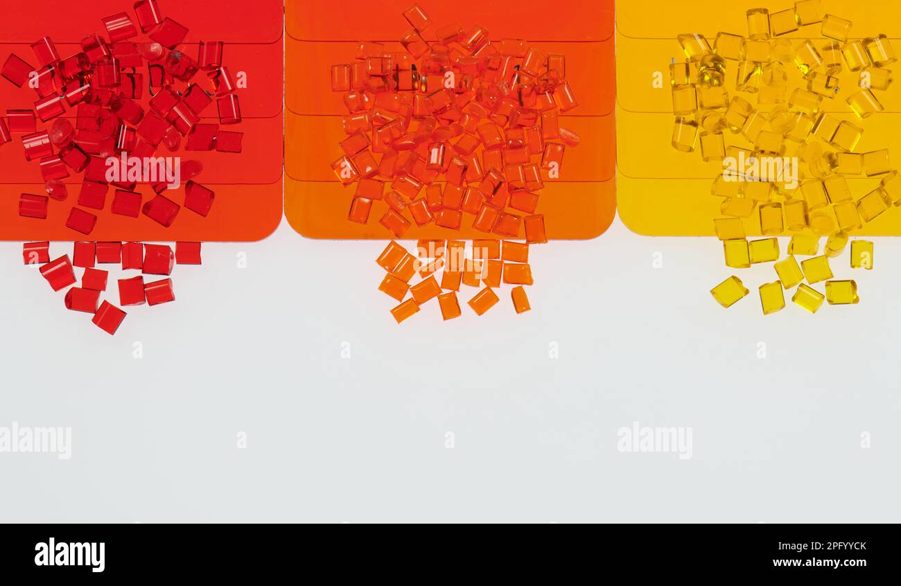 multicolored transparent plastic granulates with its color samples plates on white Stock Photo