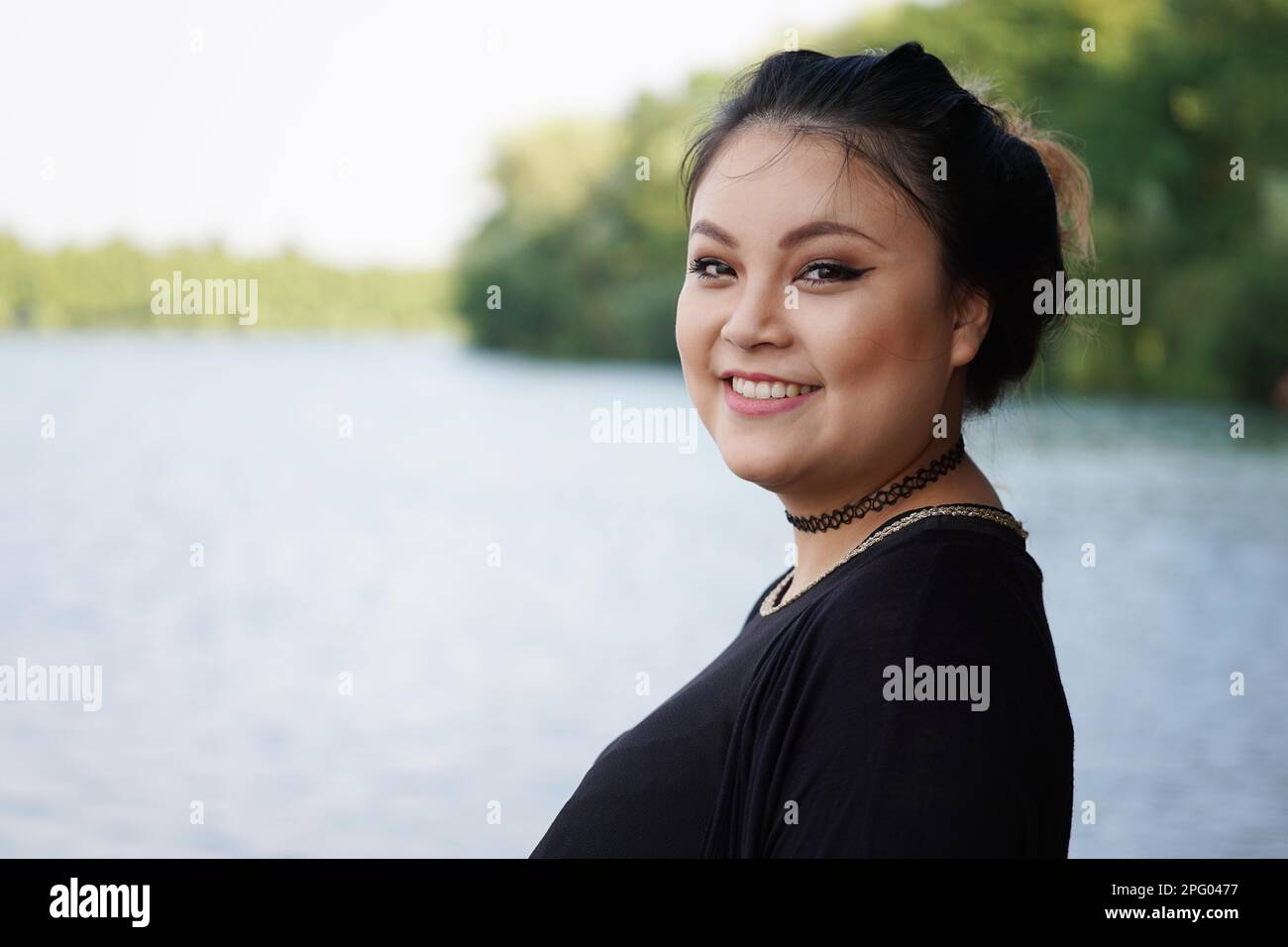 happy young asian woman standing at lakeside Stock Photo