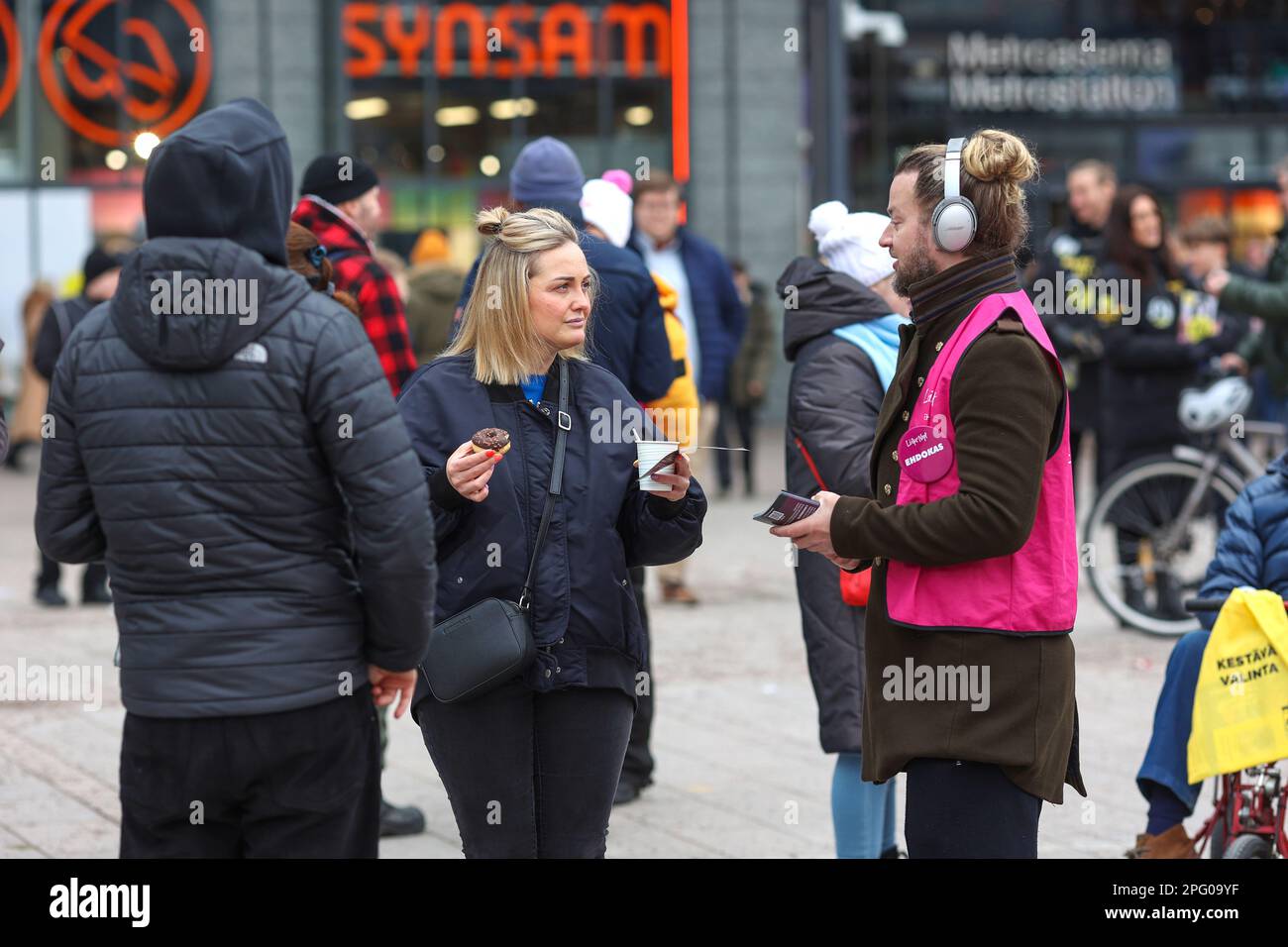 Election campaign members of Movement Now (Liike Nyt) party distribute leaflets and coffee with sweets. The Parliamentary Elections of 2023 in Finland will be held on Sunday 2 April 2023. Party candidates held election campaigns in the center of Helsinki, in front of Kamppy Shopping Center at Narinkka Square. Stock Photo