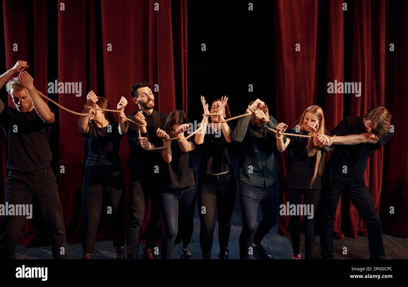 Knot in the hands. Group of actors in dark colored clothes on rehearsal