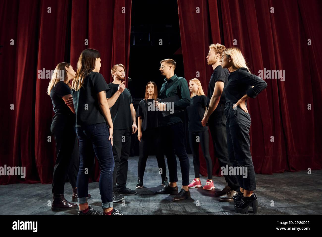 Group of actors in dark colored clothes on rehearsal in the theater
